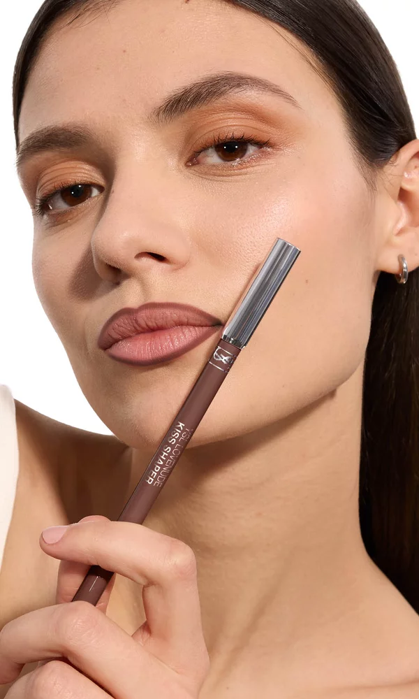 Adrienne holding YSL LOVENUDE Kiss Shaper 26 in Shade 107, full- face portrait on white background.