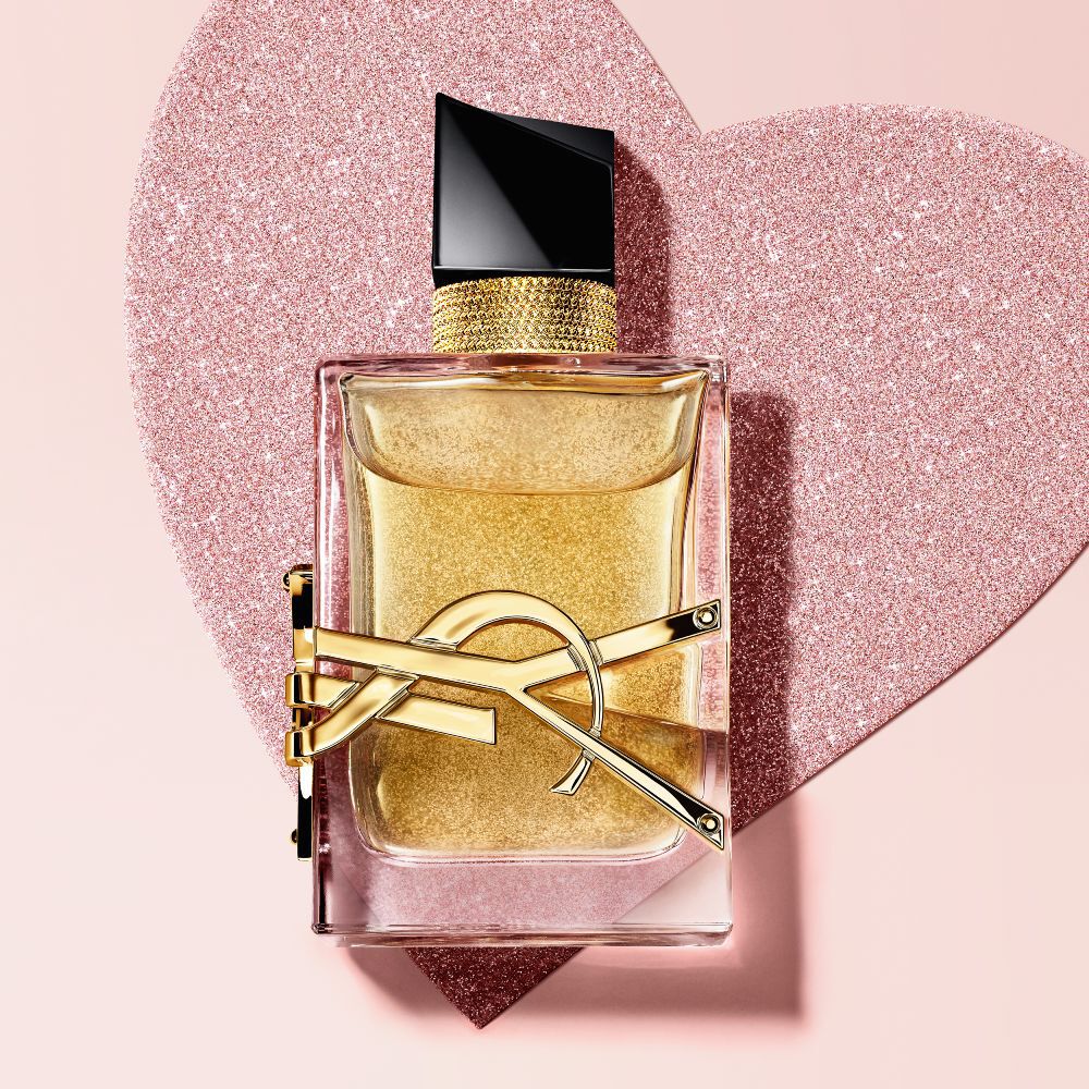 YSL Libre Eau de Parfum, a gold-toned bottle with the YSL logo, on a glittery heart background.