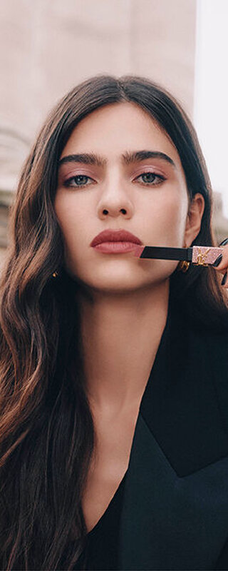 Model Loli Bahia holding YSL Rouge Pur Couture The Slim Lipstick in shade 835, applied on her lips, with a glitter case.