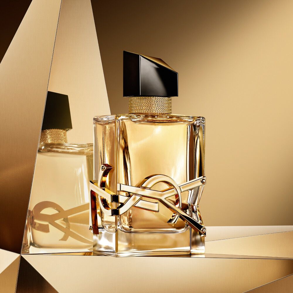 Libre eau de parfum bottle displayed on a reflective golden background.