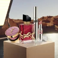 Libre berry crush perfume, Loveshine stardust, Lash Latex mascara, and Make Me Blush Powder on a beige pedestal.