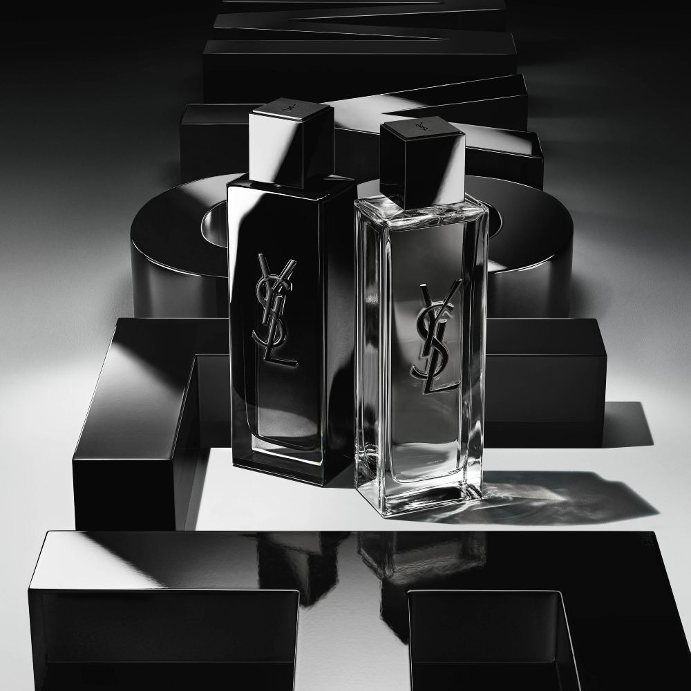High-angle view of MYSLF Eau de Toilette Intense bottles arranged on large black 3D letters spelling MYSLF laid flat on the ground.