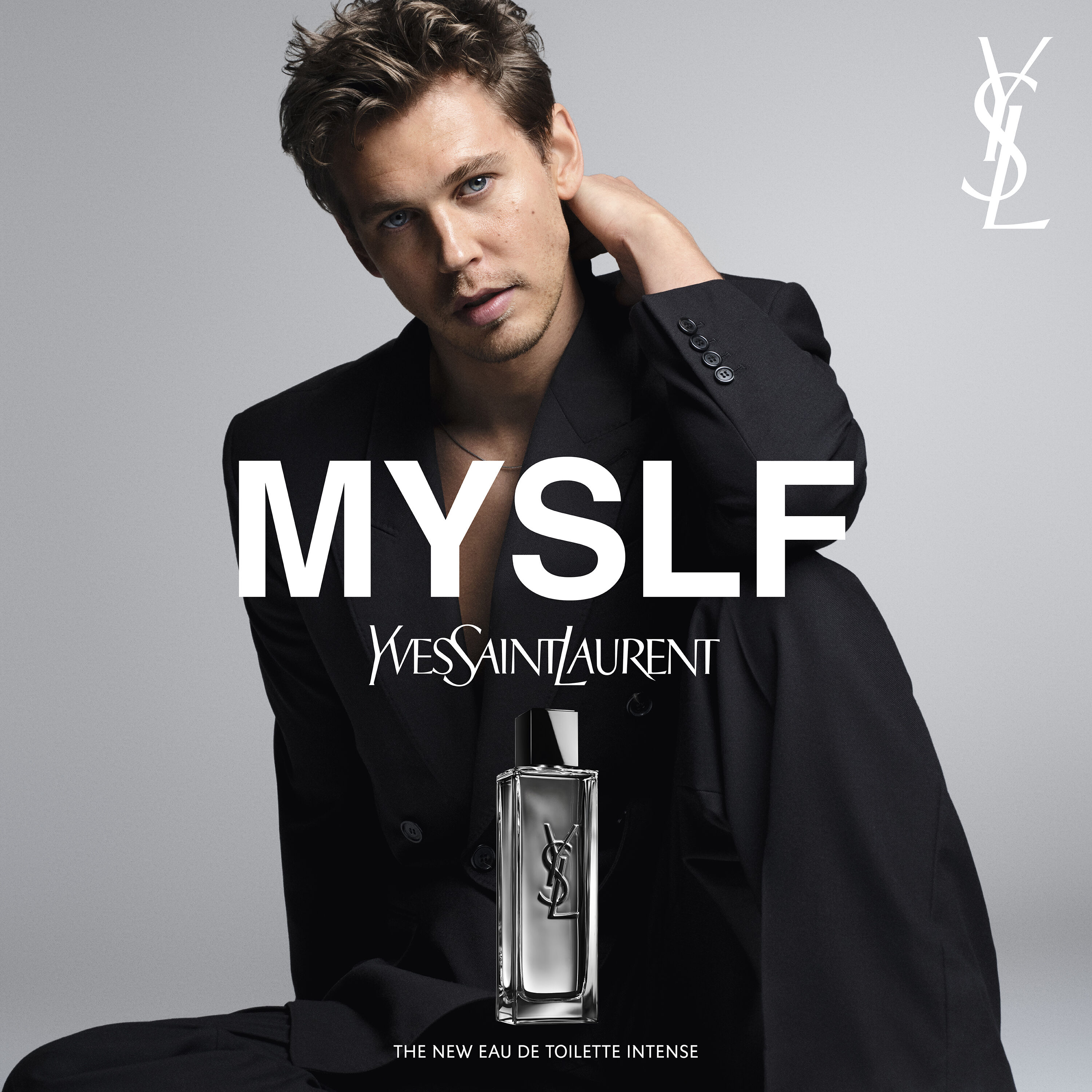 Austin Butler posing in a black suit for the MYSLF campaign with the MYSLF Eau de Toilette Intense bottle in the foreground.