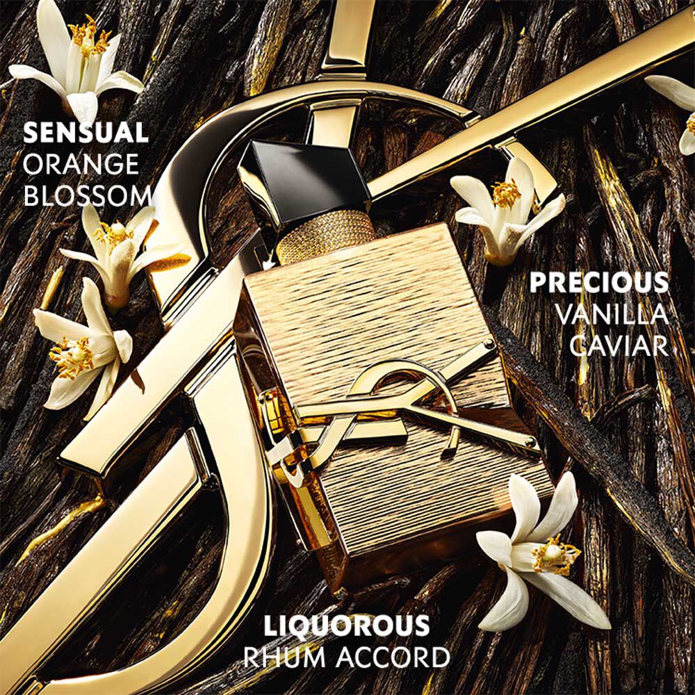 Libre Vanille Couture bottle with gold accents, surrounded by vanilla flowers and rhum accord on a textured background.