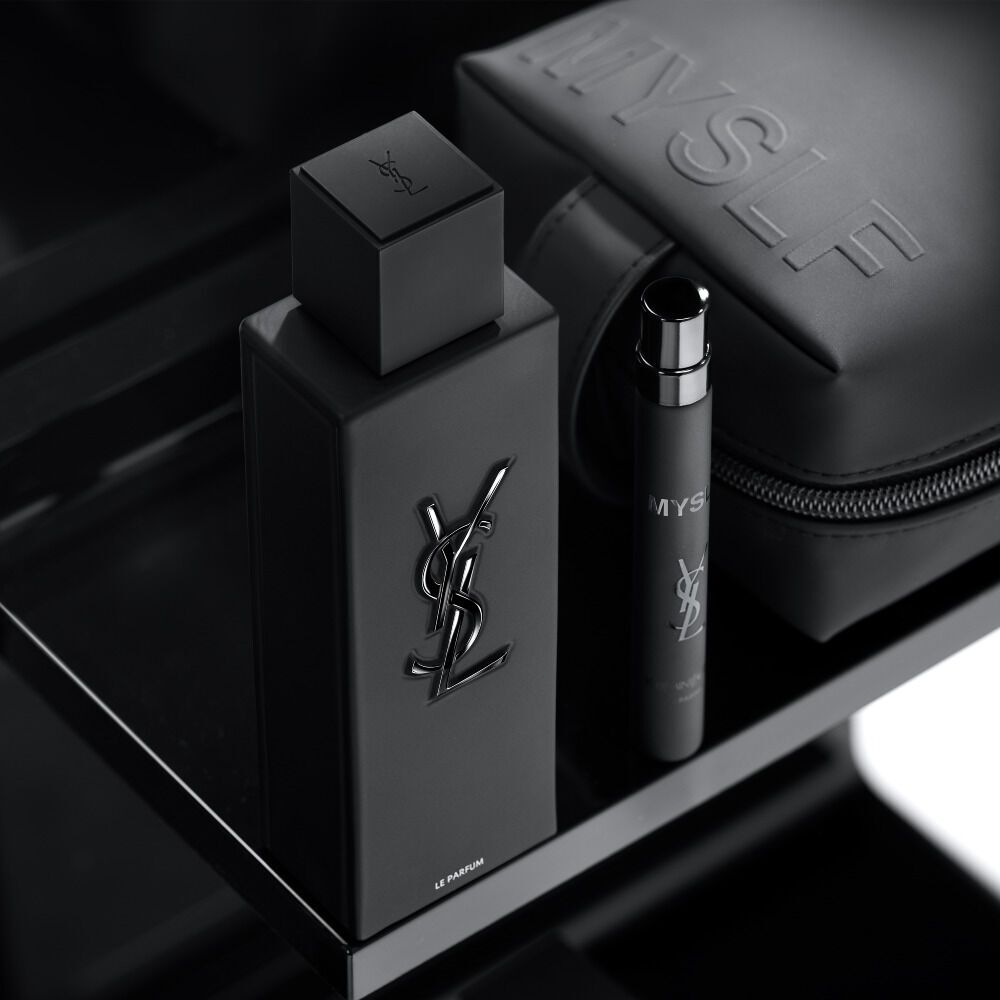 A black textured cosmetic travel bag and a collection of MYSLF products, including a bottle and a smaller vial, arranged on a dark table surface.