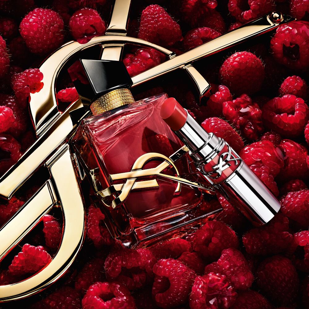 Libre Eau de parfum Berry Crush and Loveshine lipstick in Berry Crush, with the Cassandre logo, on a bed of raspberries.