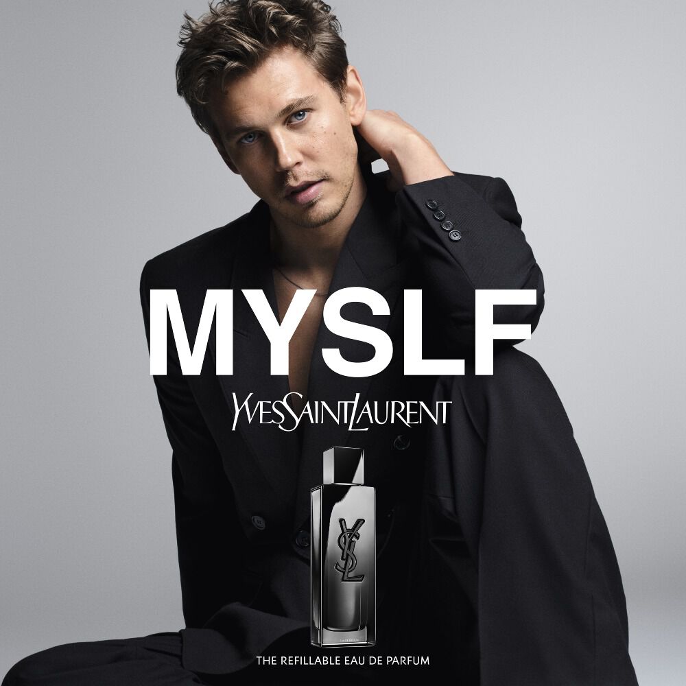 Austin Butler posing in a black suit for the MYSLF campaign with the MYSLF Eau de Parfum bottle in the foreground.