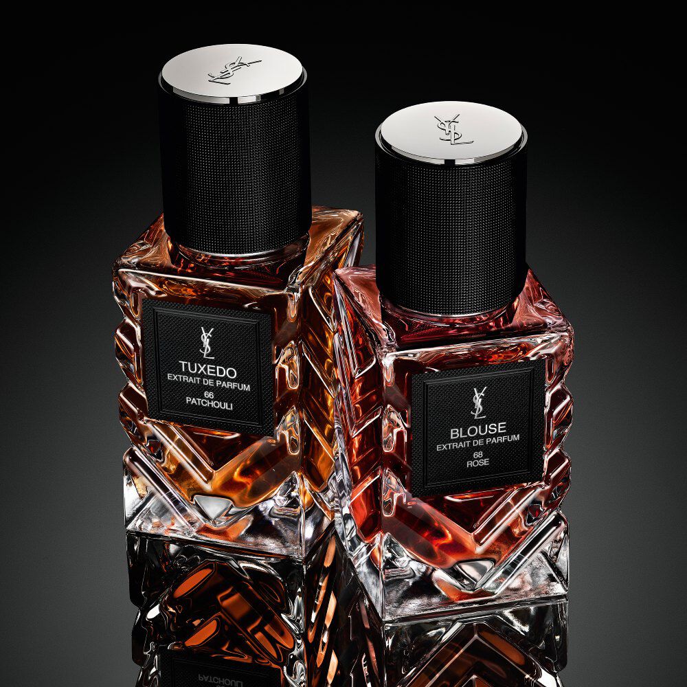YSL Le Vestiaire des Parfums Tuxedo and Blouse Extrait de Parfum, faceted bottles with black caps, on a reflective black surface.
