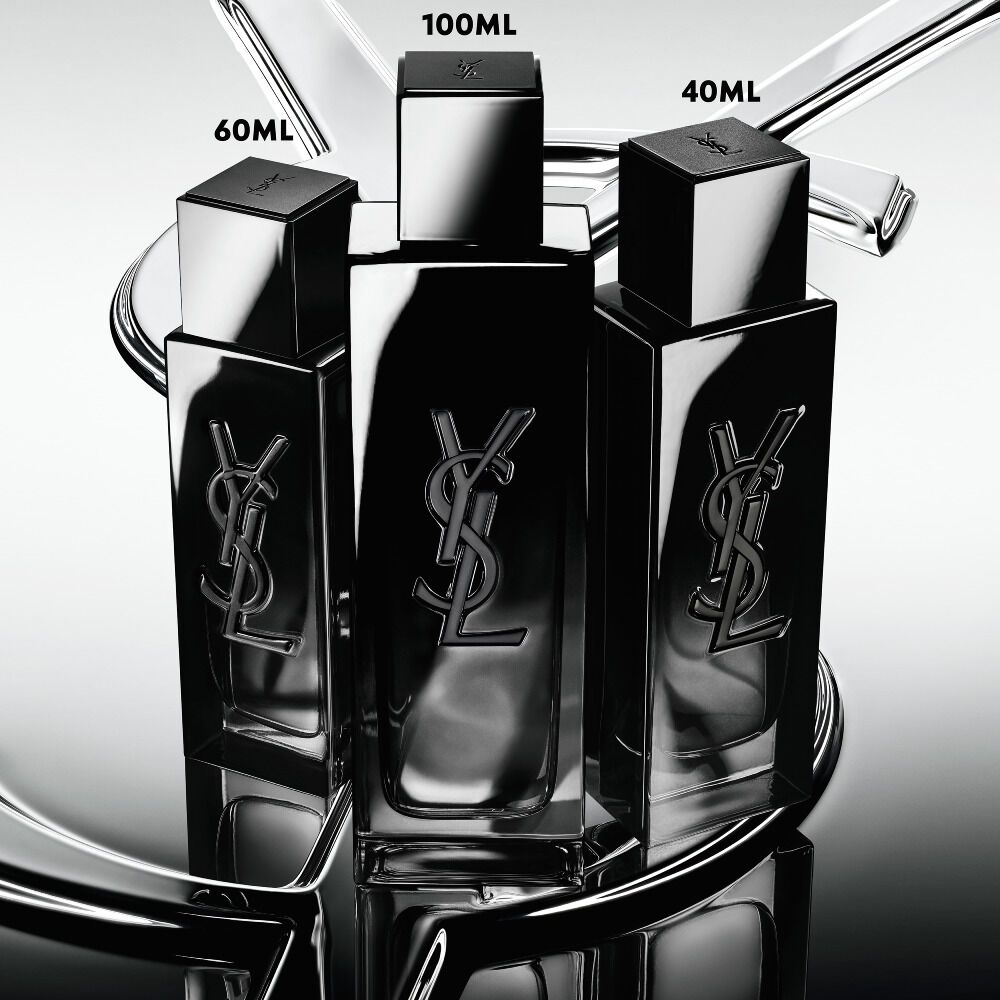 Three MYSLF Eau de Parfum bottles in 40ml, 100ml and 60ml sizes standing on a large YSL Cassandre logo with a reflective mirror effect.