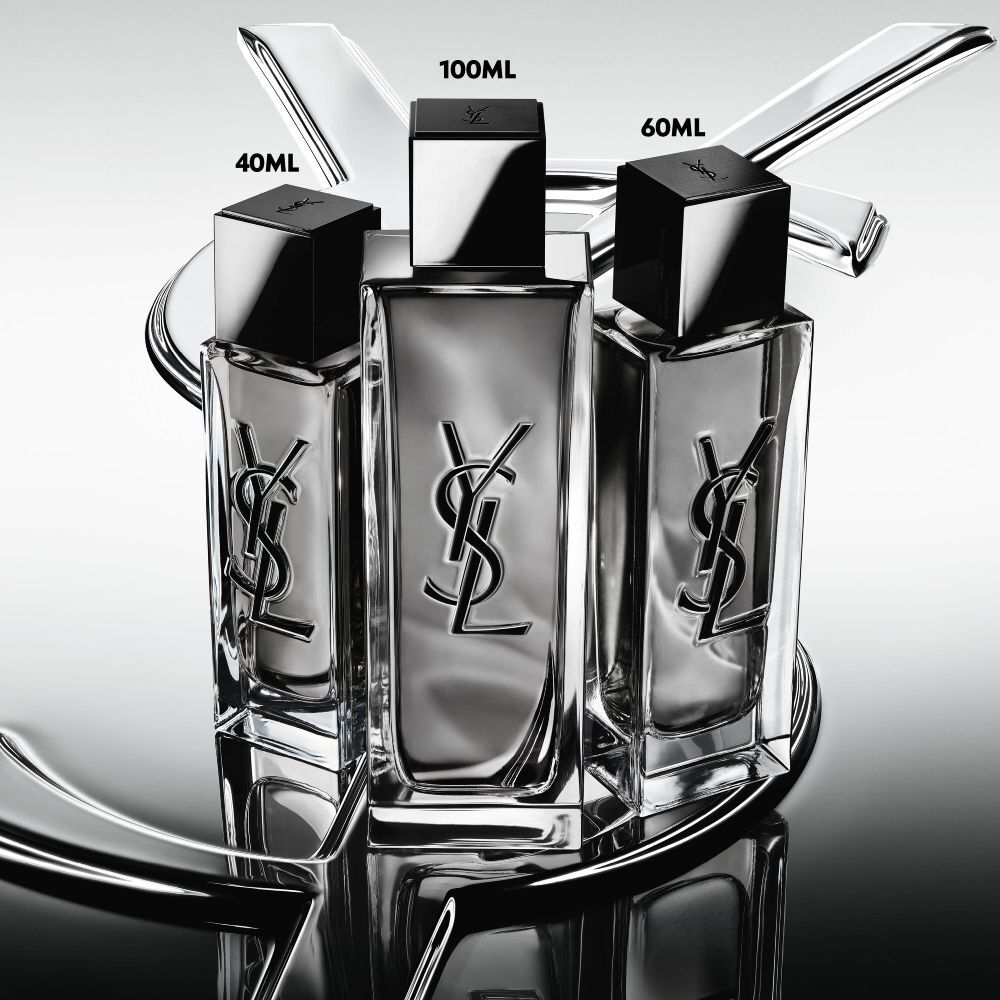 Three MYSLF Eau de Toilette Intense bottles in 40ml, 100ml and 60ml sizes standing on a large YSL Cassandre logo with a reflective mirror effect.