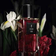 COEUR Eau de Parfum by YSL bottle surrounded by noble Iris pallida and red amber on a dark background.