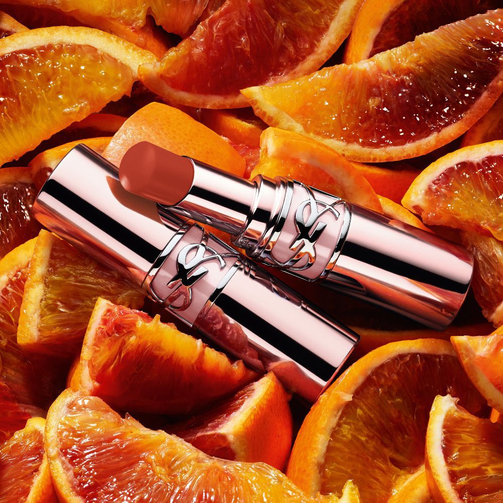 YSL LOVESHINE CANDY GLOW lip balm shade 12B Sweet Tangerine packshot placed on fresh orange slices.