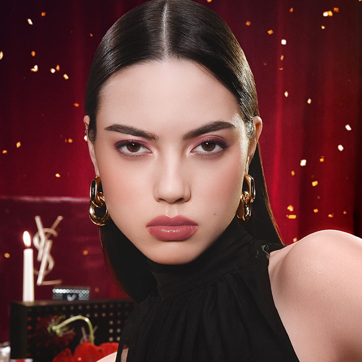 Model wearing a bold Fresh Rosé look on fair skin, set against a theatrical burgundy backdrop with fairy lights.