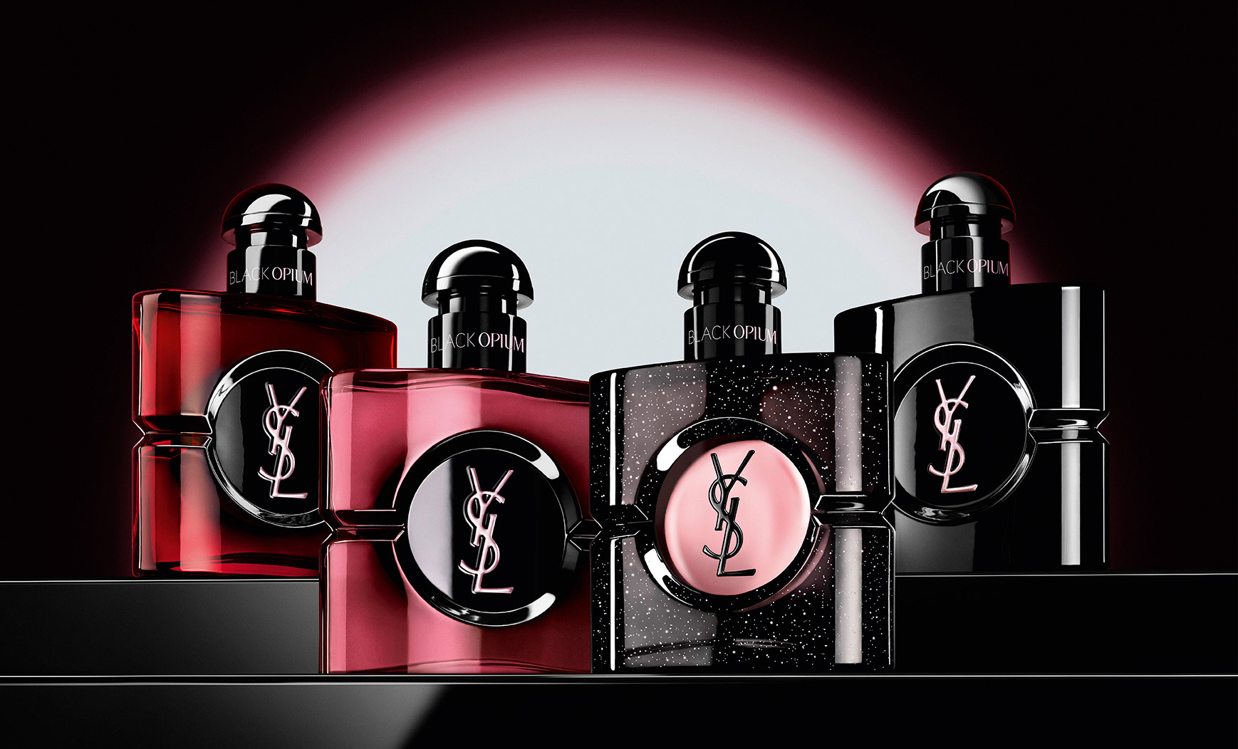 Four different Black Opium perfume bottles displayed in a row on a dark, reflective surface.