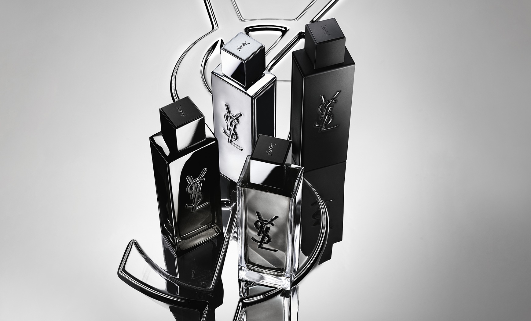 Group shot of the complete MYSLF fragrance range bottles standing on a large YSL Cassandre logo with a reflective mirror effect.