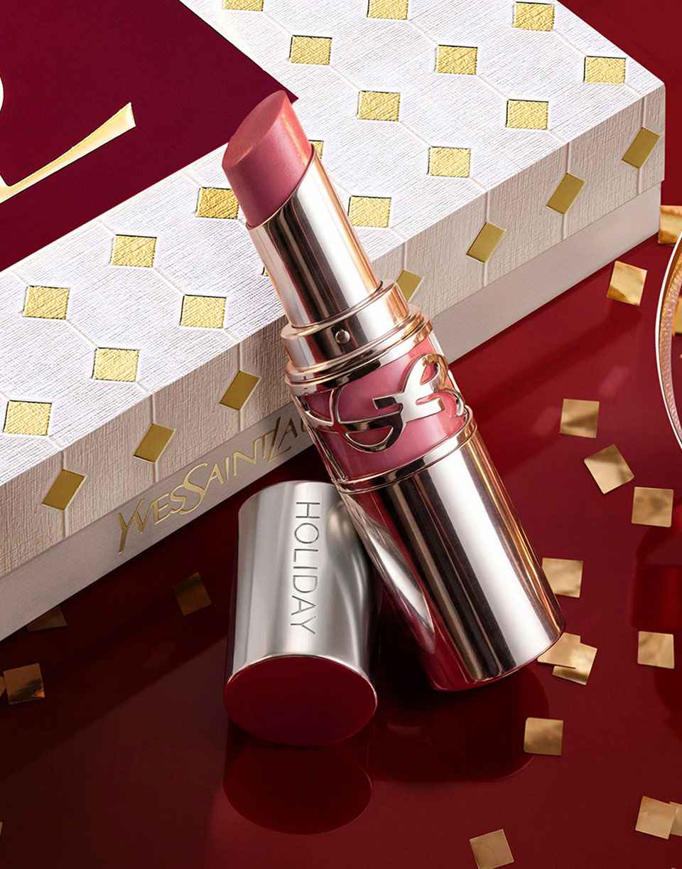 Engraved YSL Loveshine displayed with a luxury holiday gift box in the background on a festive glossy burgundy setting.