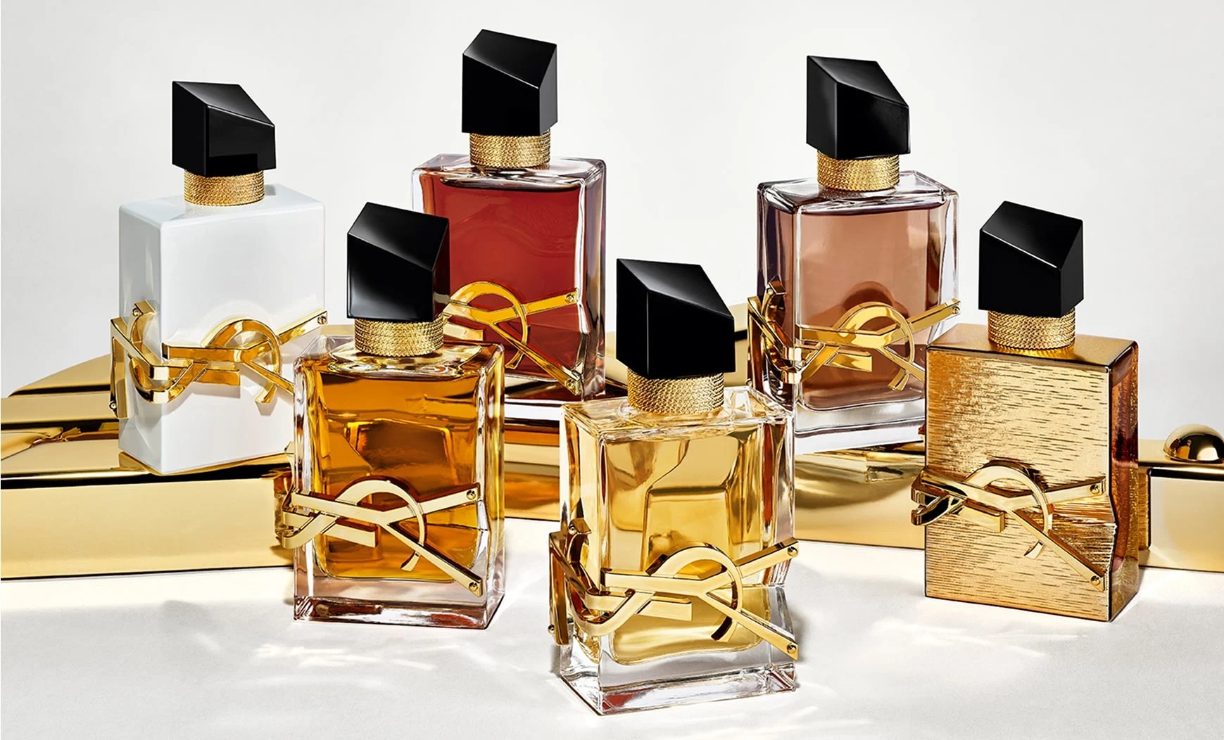 YSL Libre fragrance collection: six bottles in various shades, featuring gold accents, embedded YSL Beauty logo and black caps.