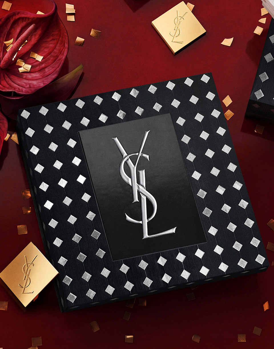 Luxury black and silver patterned YSL gift box with silver Cassandre logo and festive confetti.