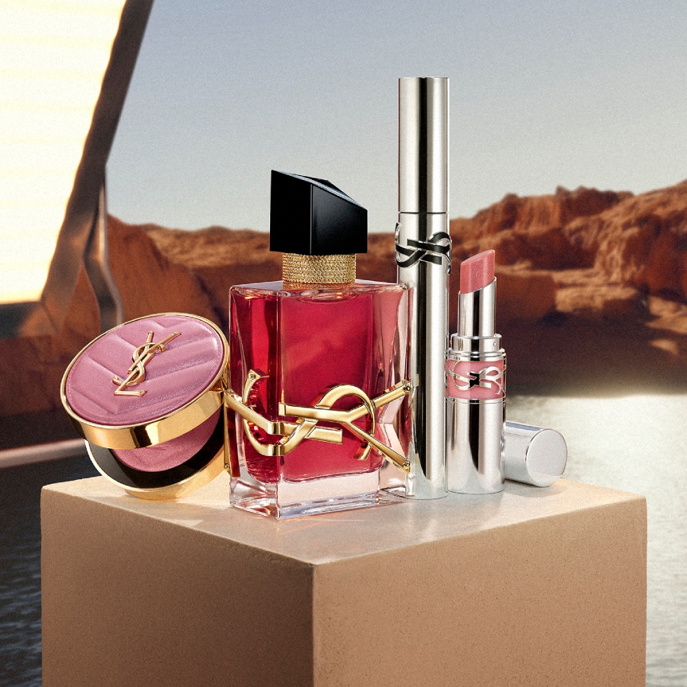 Libre berry crush perfume, Loveshine stardust, Lash Latex mascara, and Make Me Blush Powder on a beige pedestal.