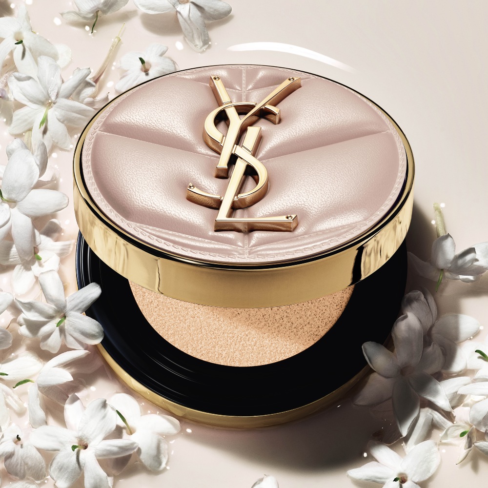 Close-up of YSL SKIN AFFAIR SOFT GLOW CUSHION in a pool of liquid foundation and jasmine flowers. Radiant, sensorial finish.