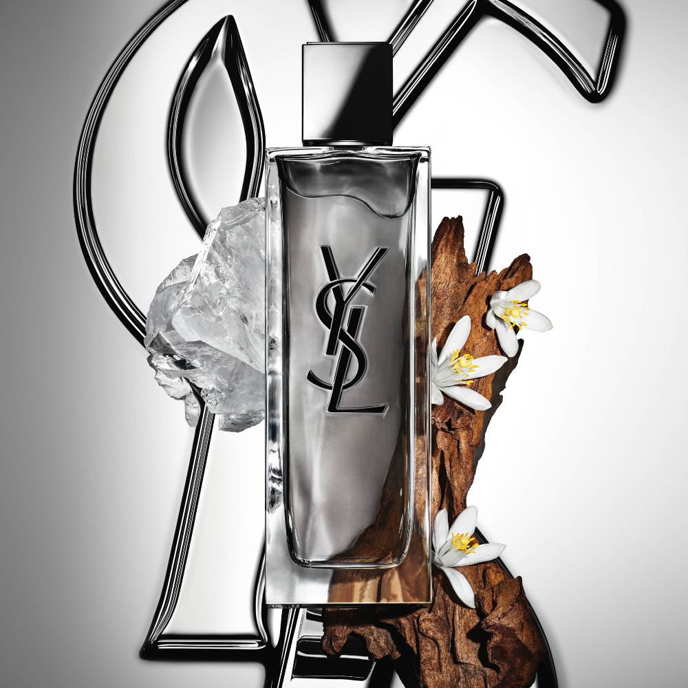 High-angle view of MYSLF Eau de Toilette Intense bottles arranged on large black 3D letters spelling MYSLF laid flat on the ground.