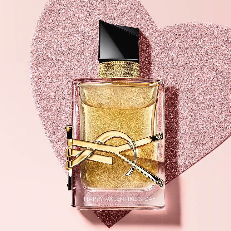 YSL Libre Eau de Parfum, a gold-toned bottle with
the YSL logo, on a glittery heart background.