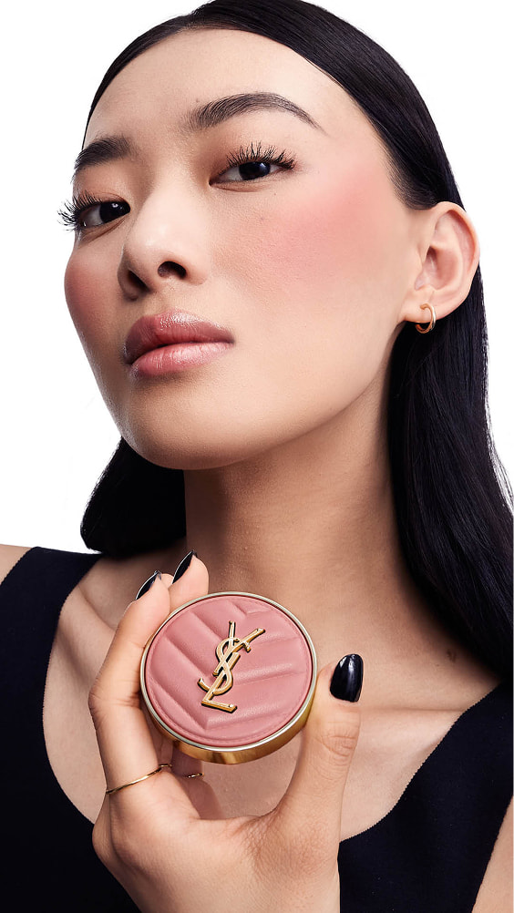 Song, light skin tone, holding a pink YSL Make Me Blush Powder Blush,
showcasing blush in shade 06 on her cheeks.