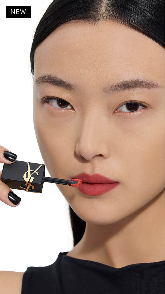 Light skin tone Asian model applying a warm-red shade of YSL THE INKS BLUR lip stain to her lips with the wand applicator.