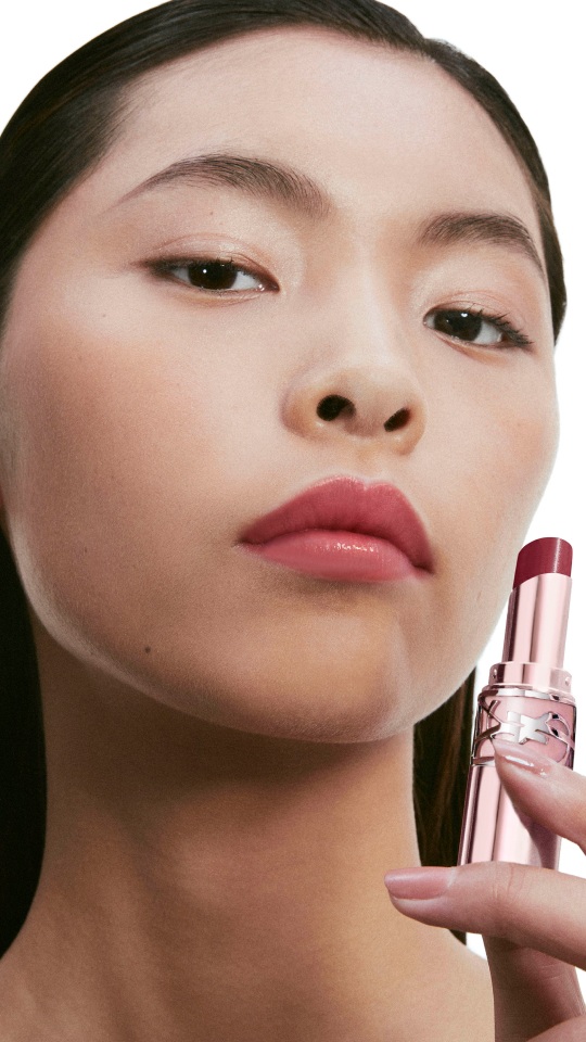 Model applying YSL LOVESHINE CANDY GLOW lip balm with luminous glossy lips.