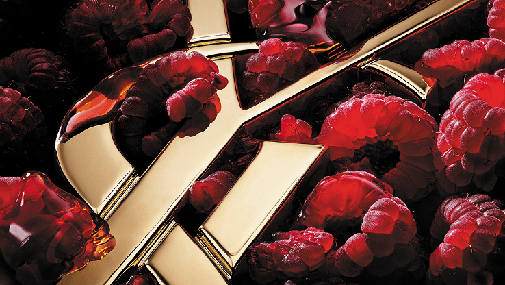 Gold YSL logo immersed in fresh raspberries with rich red tones.