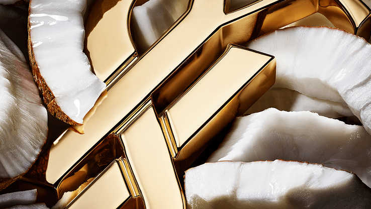 Gold YSL logo resting on creamy white coconut petals.
