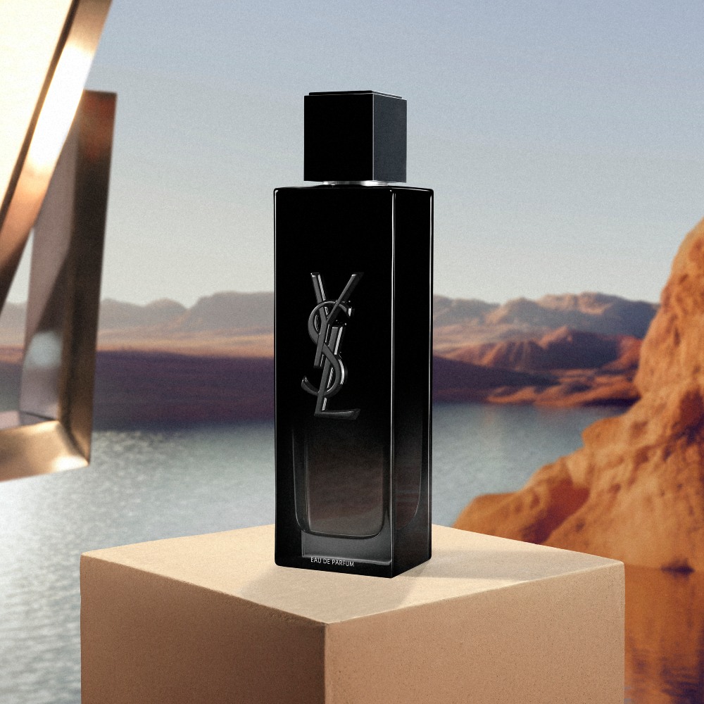 YSL MYSLF EDP 100ml perfume bottle, sleek black design, on a beige pedestal with a studio light in a desert landscape.

