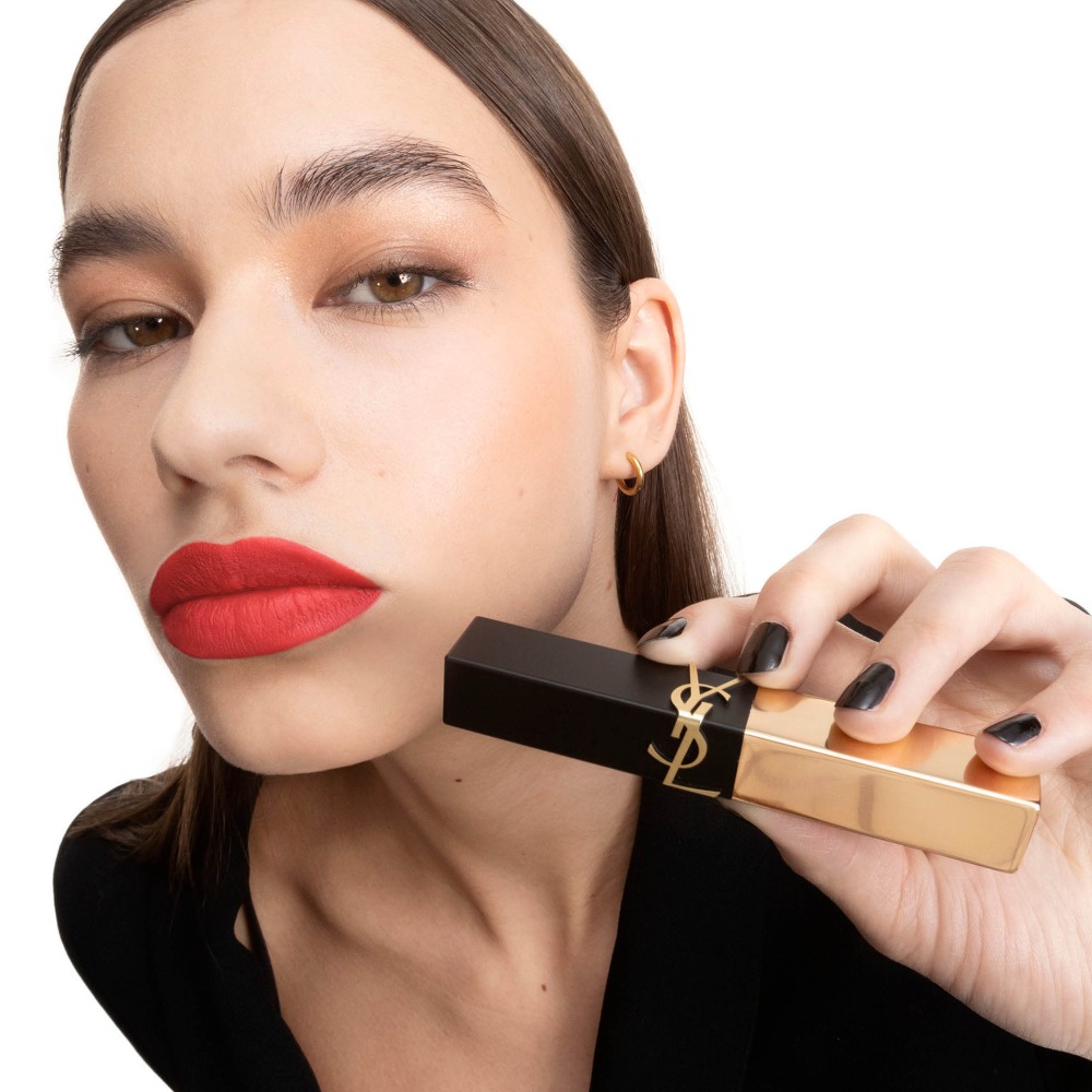 Model Anastasija holding YSL Rouge Pur Couture The Slim Lipstick in shade 21, applied on her lips, with a gold case.