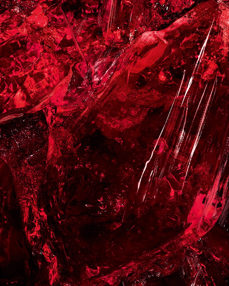 Macro shot of textured red amber
crystal, a key ingredient of CŒUR Eau
de Parfum by YSL, showing its raw
depth.