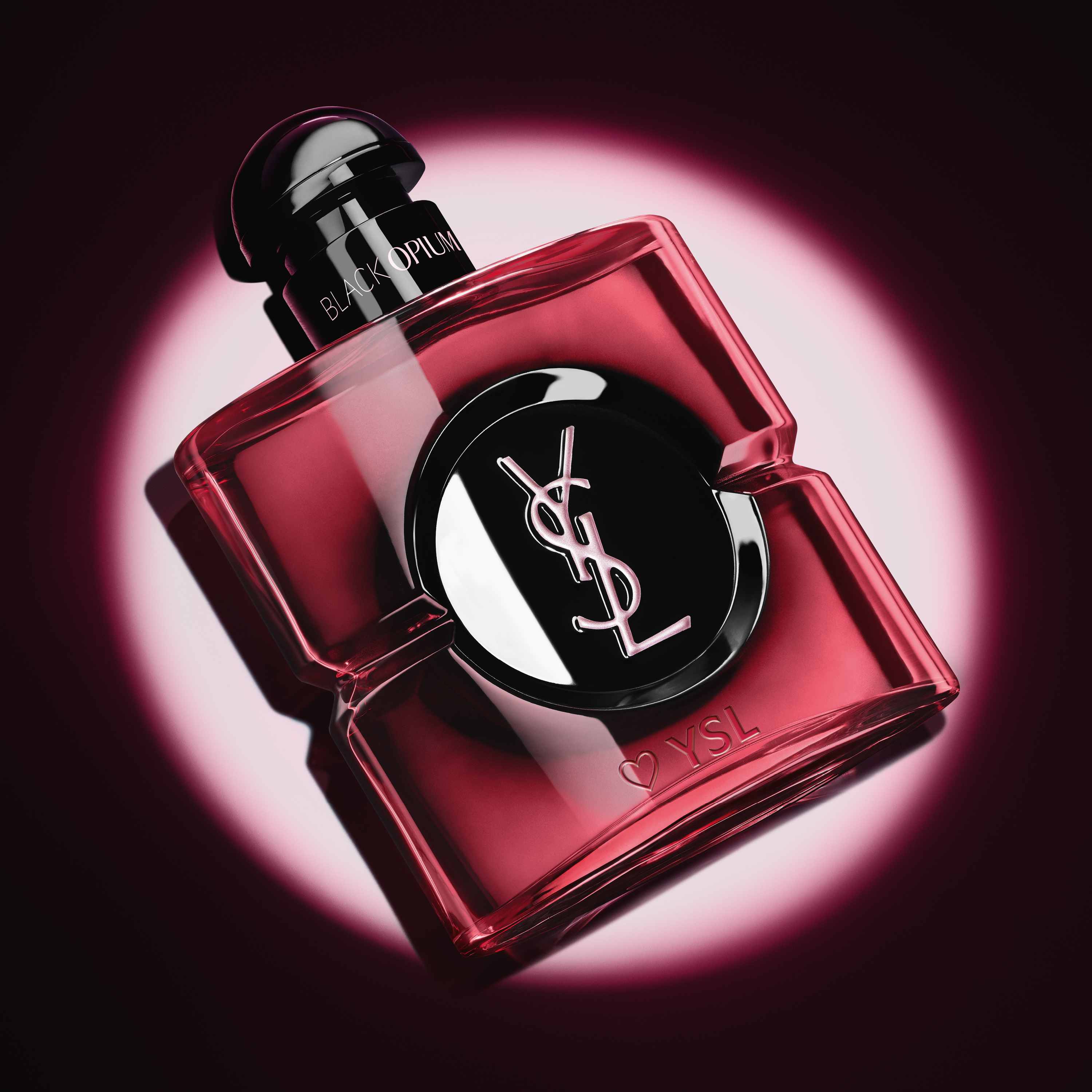 Close-up of the pink lacquered Black Opium Eau de Parfum Pink Glaze bottle with a heart and YSL engraving at the base.