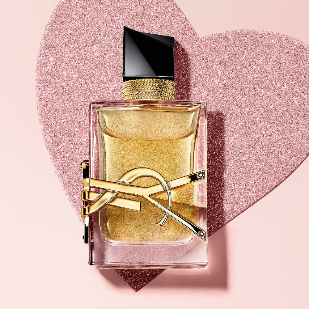 YSL Libre Eau de Parfum, a gold-toned bottle with
the YSL logo, on a glittery heart background.