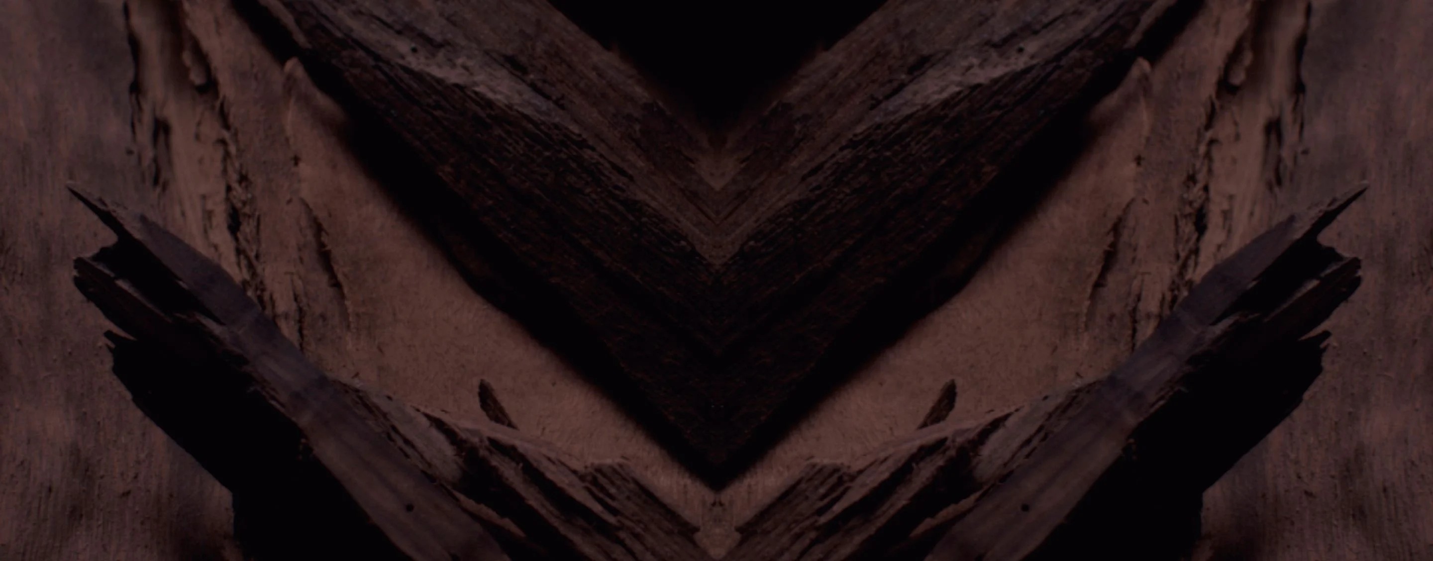 Dark, textured background with a prominent chevron pattern in
deep browns and blacks, designed for YSL LVP Extrait de Parfum
product display.