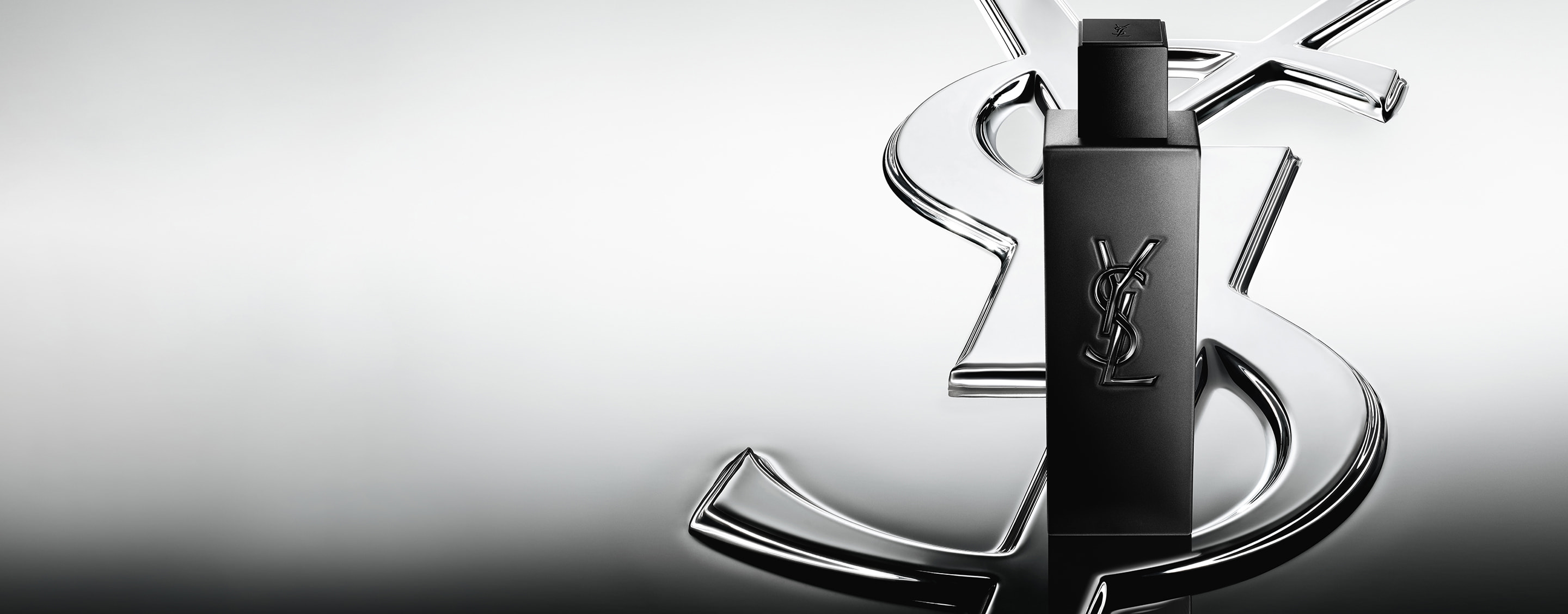 MYSLF Le Parfum matte black bottle standing on a large YSL Cassandre logo with a reflective mirror effect.