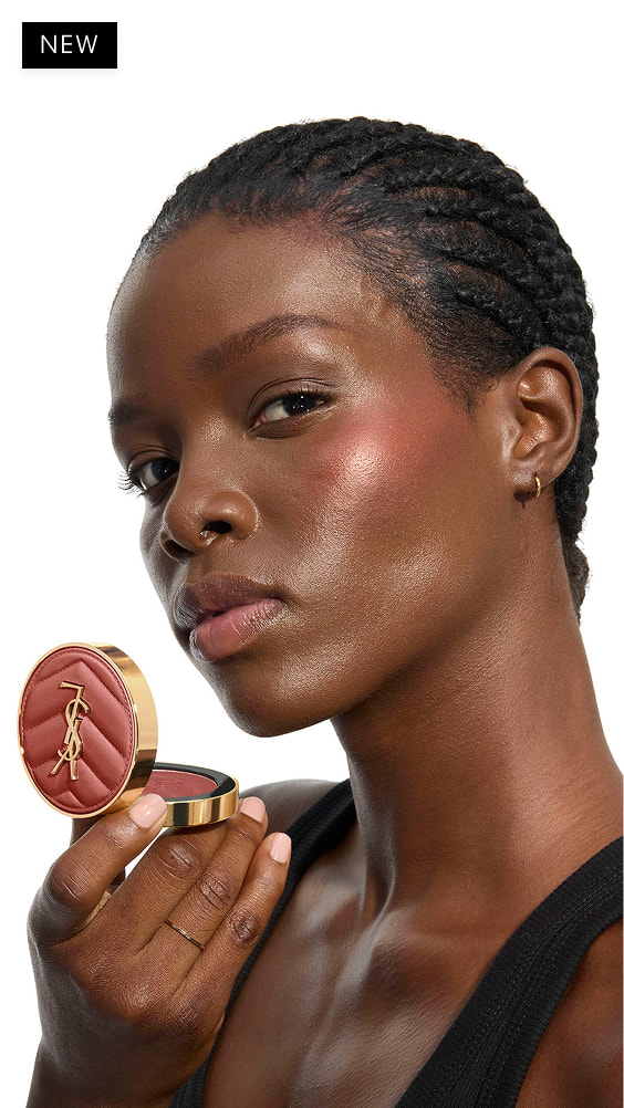 Elaine, dark skin, holding an open reddish-brown YSL Make Me Blush
Powder Blush in shade 12, showcasing blush on her cheek.