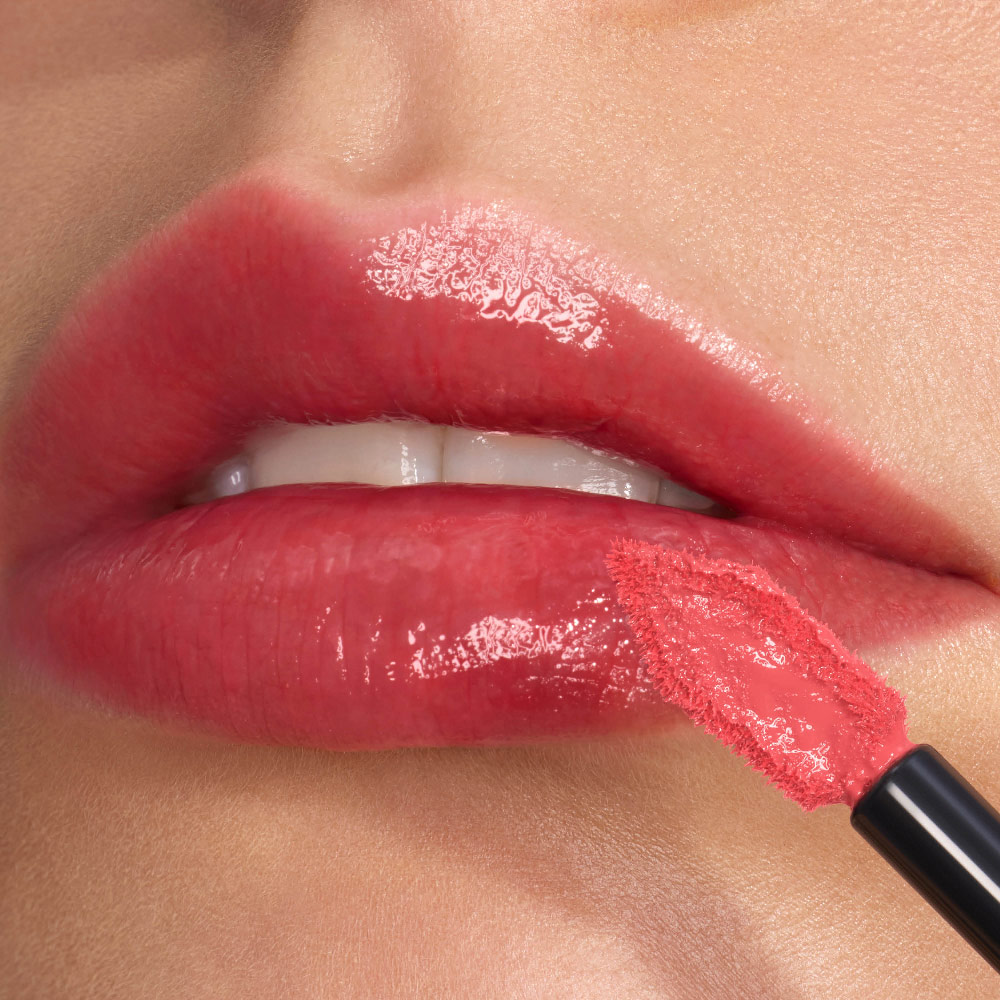 Close-up of glossy, high-shine lips being precisely lined with the angled, flat-tipped YSL lip stain applicator.