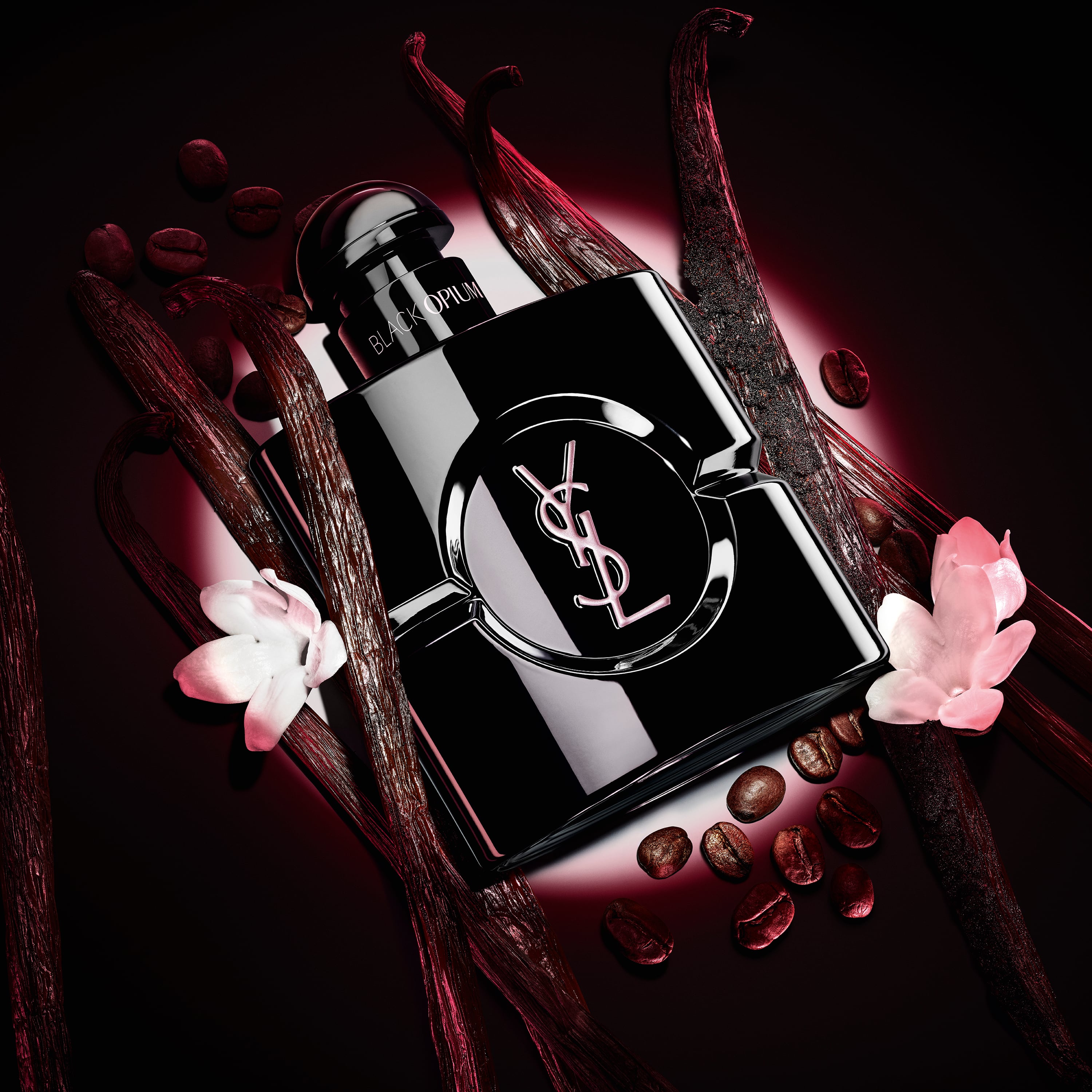 Black Opium Le Parfum bottle in glossy black, surrounded by dark vanilla pods and white jasmine.