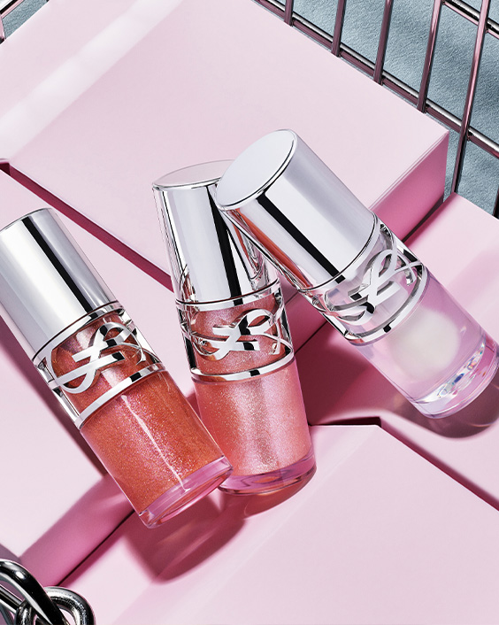 Three YSL Loveshine in shades 10, 11, and 12 displayed on purple blocks in a metallic basket.