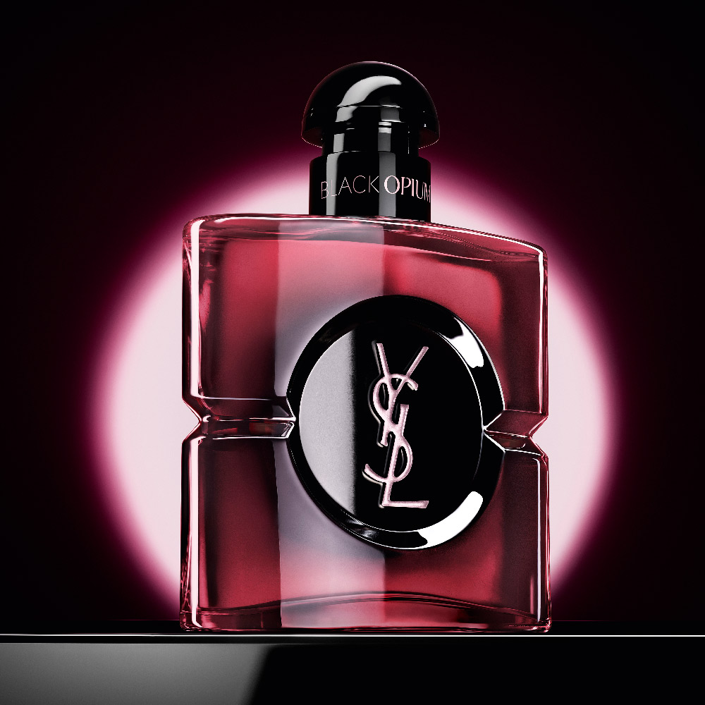 Black Opium Eau de Parfum Pink Glaze bottle highlighted by a pink circular glow on a dark background.