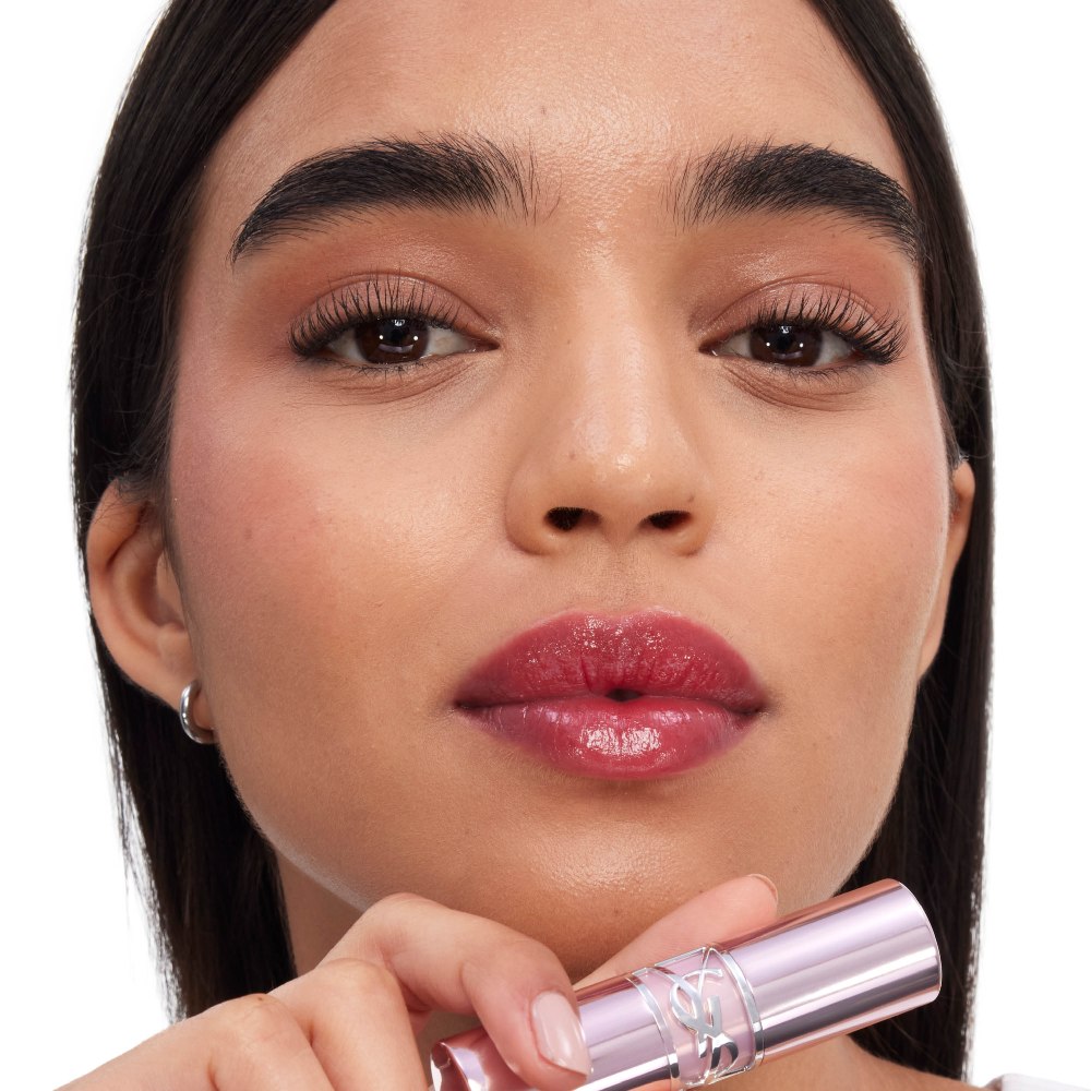 Model applying YSL LOVESHINE CANDY GLOW lip balm for luminous hydrated lips.