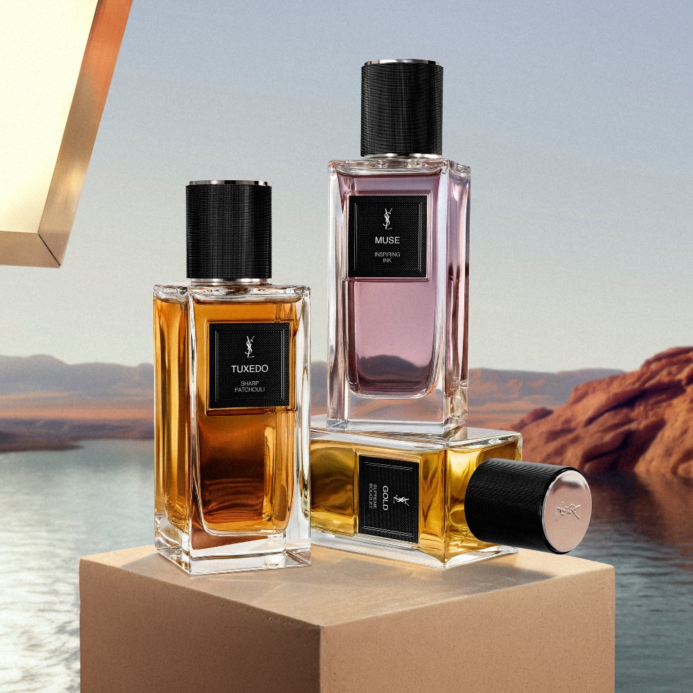 Le Vestiaire Des Parfums fragrances: MUSE, TUXEDO, and GOLD bottle, on a pedestal in a desert landscape.