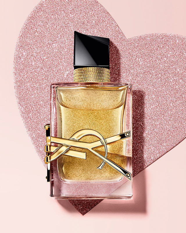 YSL Libre Eau de Parfum, a gold-toned bottle with the YSL logo, on a glittery heart background.