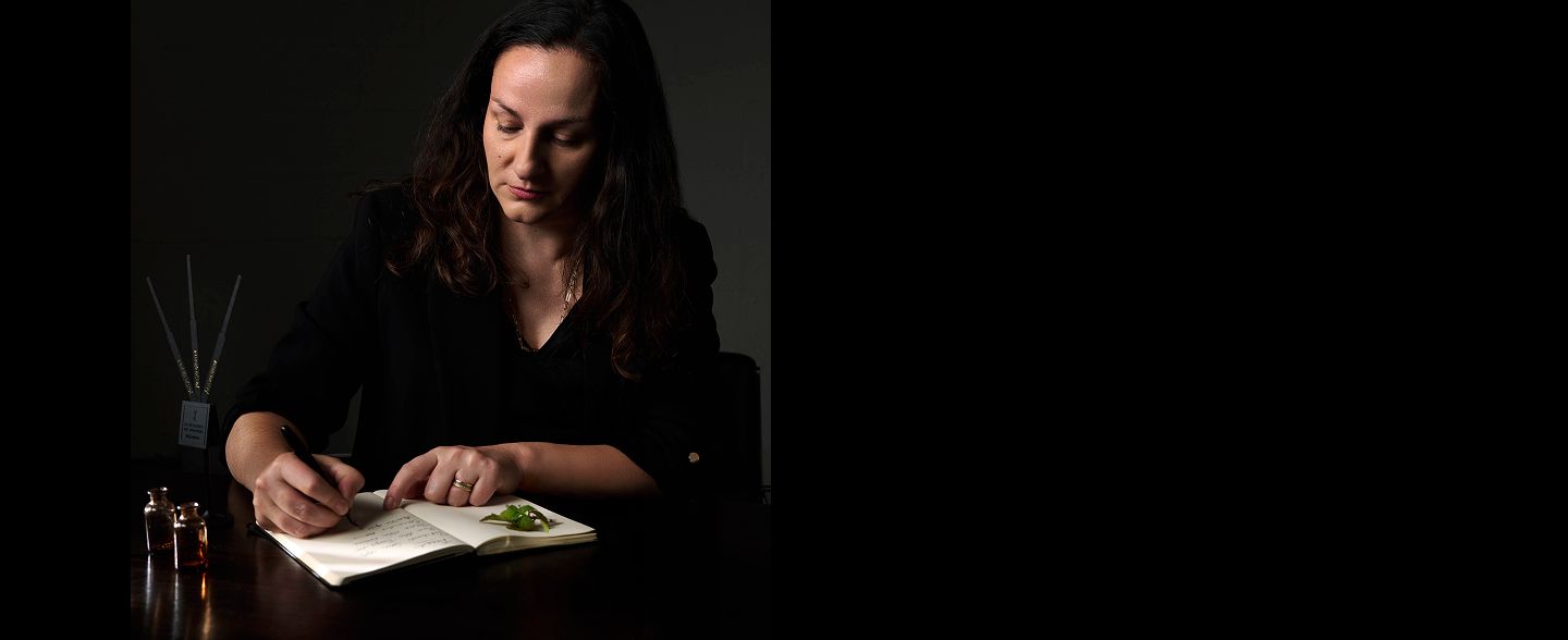 Perfumer Juliette Karagueuzoglou writing notes at a desk with a
notebook, capturing the essence of creation.