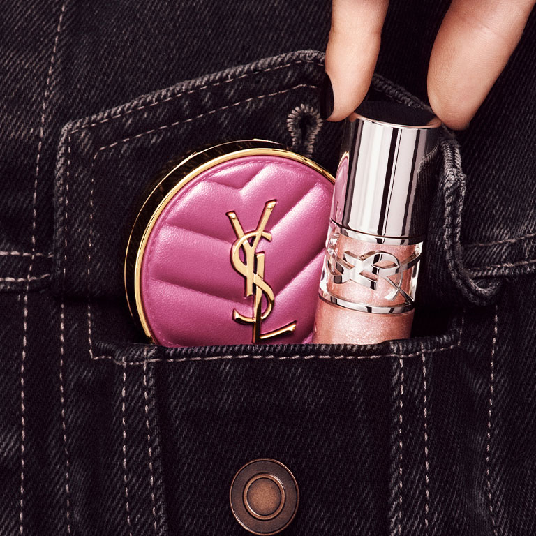 Hand placing YSL LOVESHINE Lip Oil Gloss and pink Make Me Blush compact into a denim pocket in shade 10