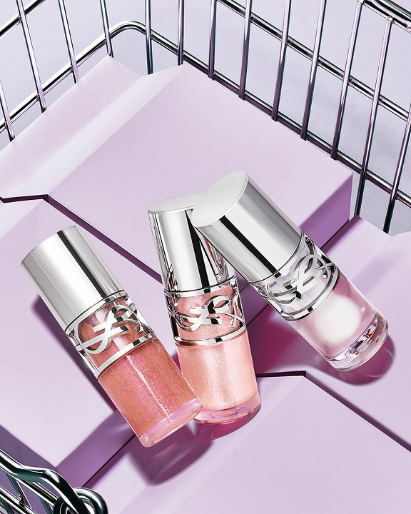 Three YSL Loveshine in shades 10, 11, and 12 displayed on purple blocks in a metallic basket.