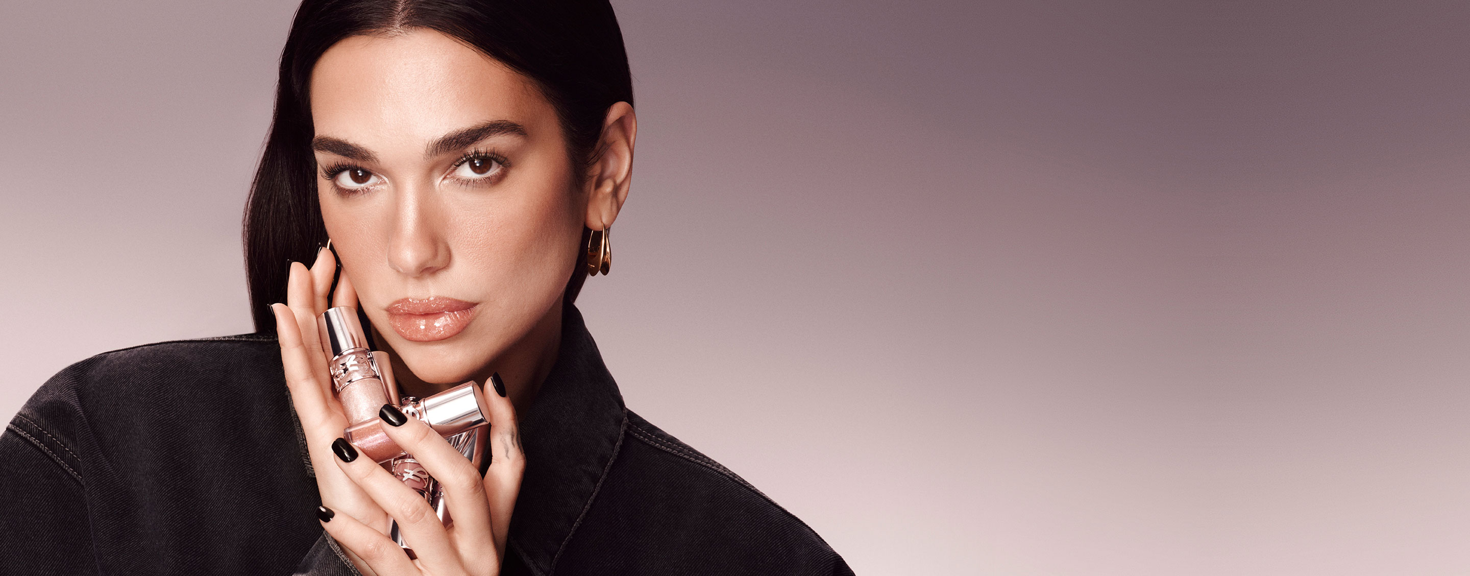  Dua Lipa, YSL Beauty ambassador, holding two YSL LOVESHINE Plumping Lip Oil Glosses, with a subtle gradient background.